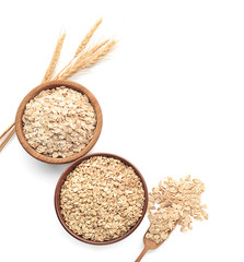 Bowls with raw oatmeal on white background