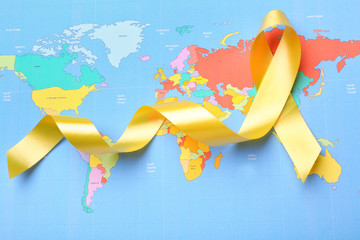 Yellow ribbon on world map. Cancer concept