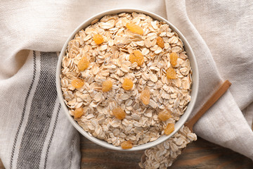Bowl with oat flakes and raisins on wooden table