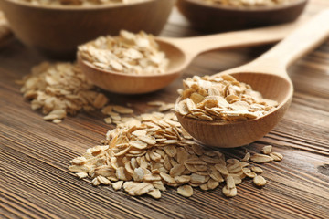 Spoons with oat flakes on wooden table