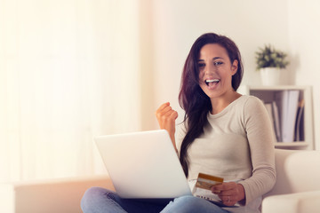 Joyful woman using laptop and buying online with credit card