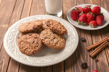 Plate with delicious oatmeal cookies and fresh strawberries on wooden background