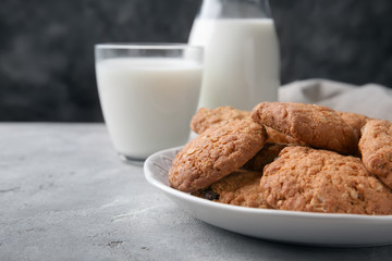 Plate with delicious oatmeal cookies and milk on table