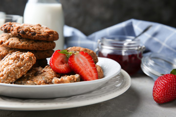 Plate with delicious oatmeal cookies and fresh strawberries on table