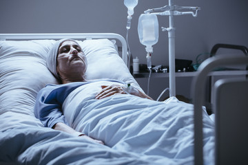 Sick and lonely senior woman with leukemia during chemotherapy in the hospital
