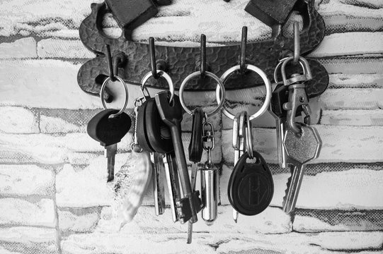 Key holder with keys hanging on the wall. Black and white photo, closeup