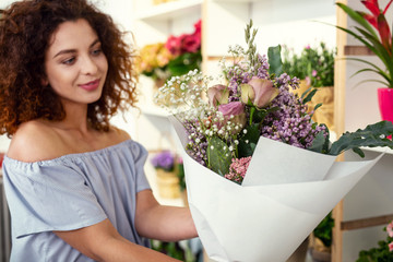 Beautiful flowers. Selective focus of a beautiful bouquet being held by a positive cheerful woman