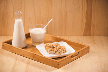 Bottle with milk and glass of milk at wooden table with almond candies.