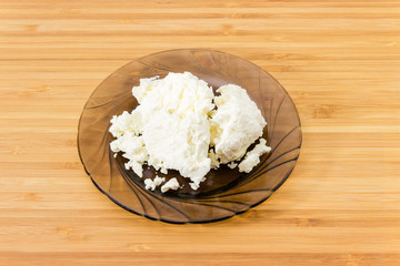 Cottage cheese on glass dish on bamboo wooden surface