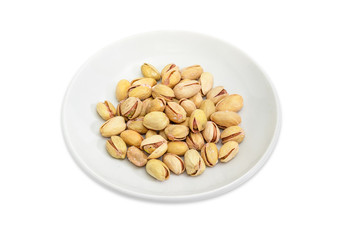 Roasted salted pistachio nuts with shells on the white saucer