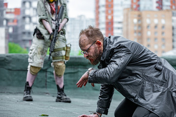 Naklejka premium Woman soldier, spy agent killer or police woman with a gun in her hand holding at gunpoint a man lying on the ground