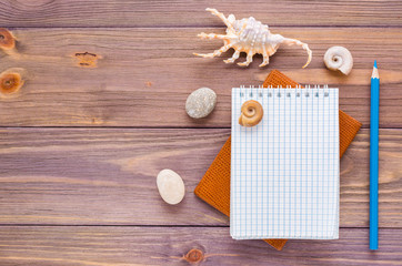Clean open notepad for writing, pencil, passport and seashell on a wooden background. Top view. Vacation concept.