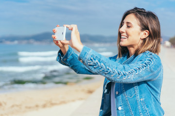lächelnde junge frau macht ein foto am strand