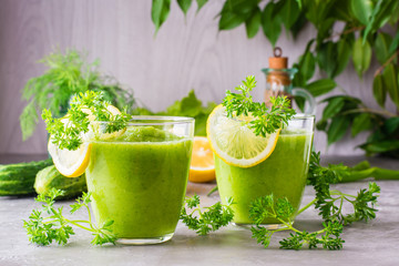 Refreshing smoothies from cucumber, green apple, fresh herbs and lemon juice in transparent glasses on the table. The concept of a healthy diet. Vegetarian menu