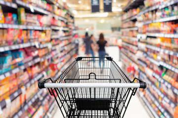 Shopping trolley in department store with goods shelf background.