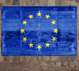 European Union flag painted on a wooden billboard  against a stone wall