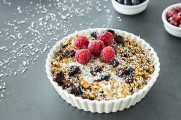 Close up of a plate with muesli, raisins, raspberries and coconut shreds