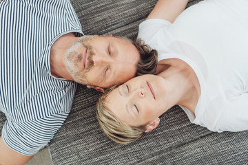 ehepaar liegt kopf an kopf auf dem sofa und hat die augen geschlossen
