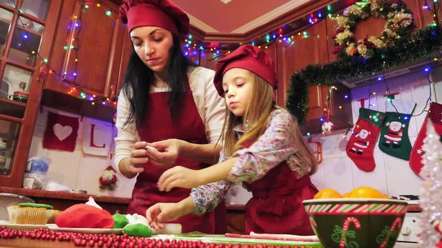 Mother and daughter are making decorations with sugar mastic for cupcake