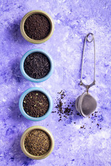 Variety of Tea Leaves in Bowls. On Purple Background.