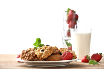 Plate with tasty oatmeal cookies and strawberry on wooden table