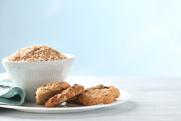 Bowl with raw oatmeal and cookies on table