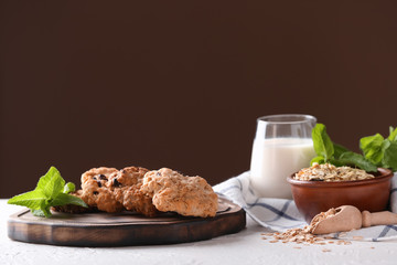 Wooden board with oatmeal cookies and mint leaves on table