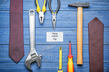 Card with text "Happy Father's Day", male ties and set of tools on wooden background