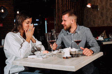Young happy couple romantic date drink glass of red wine at restaurant, celebrating valentine day
