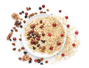 Plate with oatmeal, cranberries, raisins and walnuts on white background