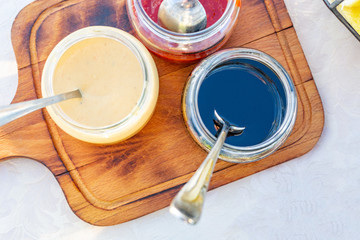 Spoon with tasty sweet sauces and jar on board, condensed milk, honey, jam