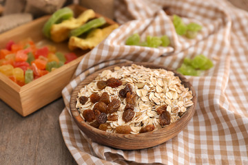 Bowl with raw oatmeal and raisins on table