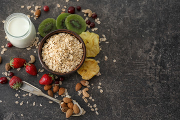 Composition with oatmeal flakes, berries and fruits on dark background
