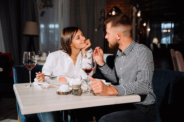 young couple on a date. A man feeds his woman a delicious dessert. Couple laughing in the restaurant