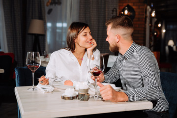 Flirting in a cafe. Beautiful loving couple sitting in a cafe enjoying in wine and conversation