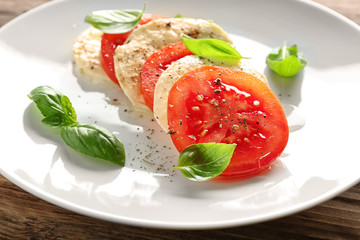 Fresh basil with tomatoes and cheese on plate, closeup