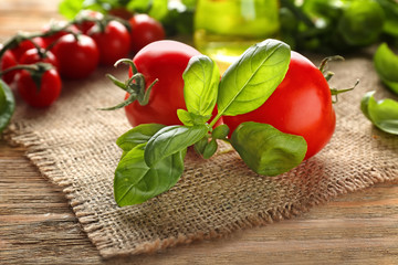 Fresh basil with tomatoes on wooden table