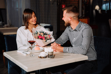 attractive young woman getting a flowers from her boyfriend while sitting in the cafe