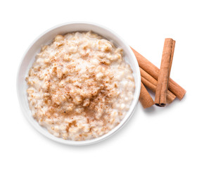 Bowl with tasty oatmeal and cinnamon on white background