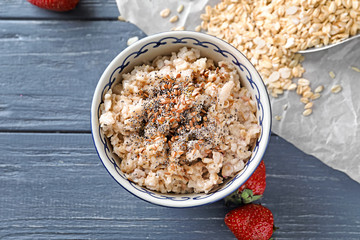 Bowl with tasty oatmeal on wooden background
