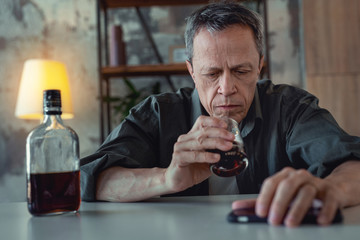 Man in despair. Grey-haired mature man feeling in despair suffering from alcohol addiction while...