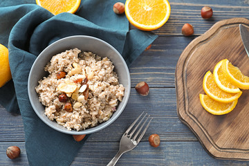 Bowl with tasty oatmeal on wooden table