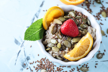 Bowl with tasty oatmeal and fruits on color background
