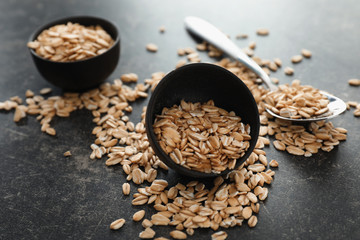Bowl with raw oatmeal on grey background