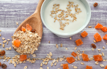 Bowl with milk and dry oatmeal on wooden table