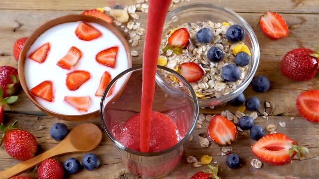 Strawberry smoothie flowing in glass in slow motion. Healthy drinking concept. Healthy breakfast with yogurt and cereals.
