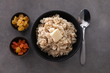 Tasty oatmeal and candied fruits on grey background