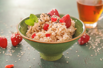 Bowl with tasty oatmeal and strawberry on color background