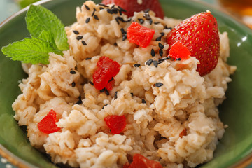 Bowl with tasty oatmeal and strawberry, closeup