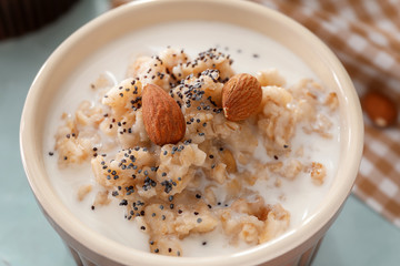 Tasty oatmeal with milk and nuts in bowl on table, closeup